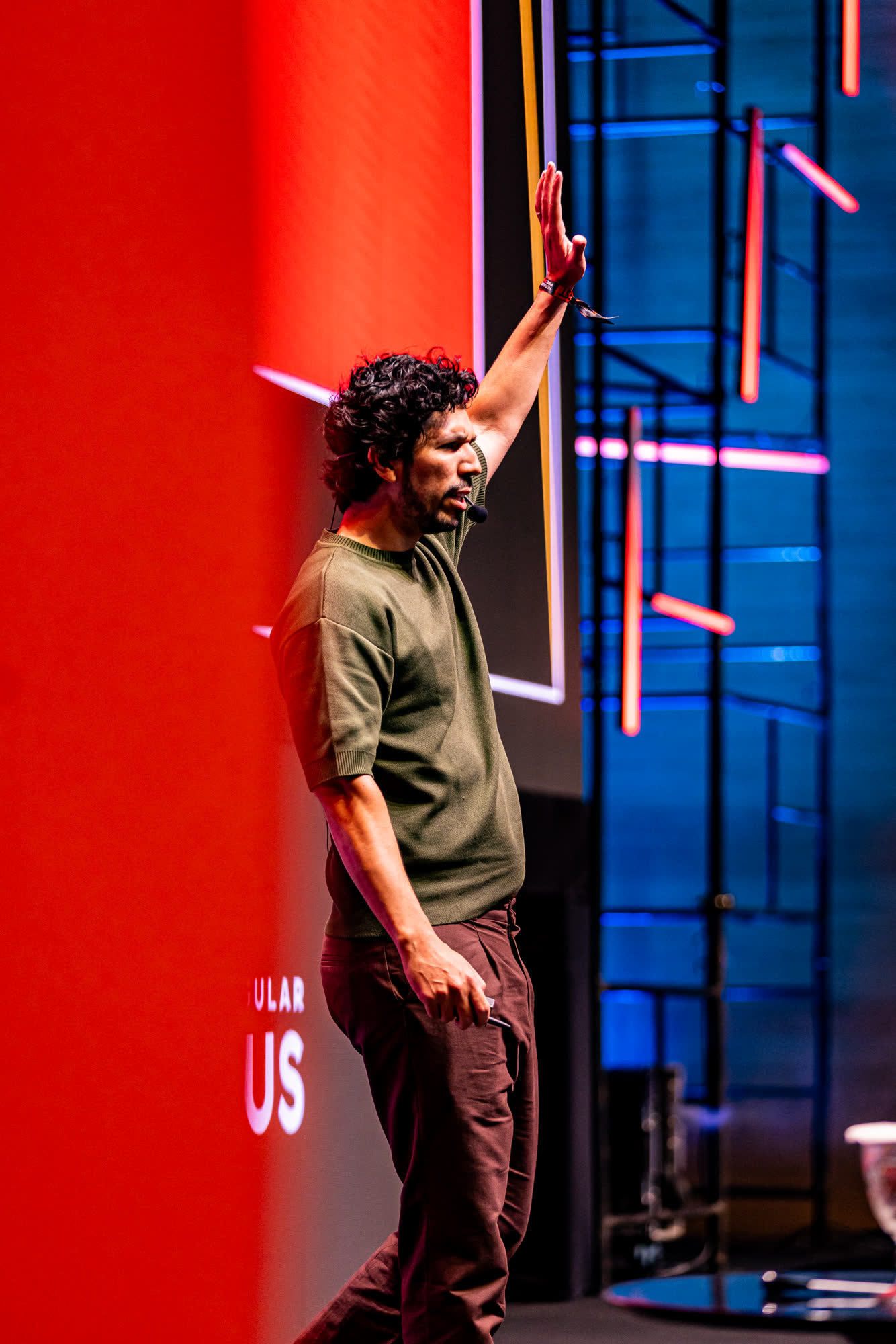 Thales Laray no palco, braço erguido apontando para o telão